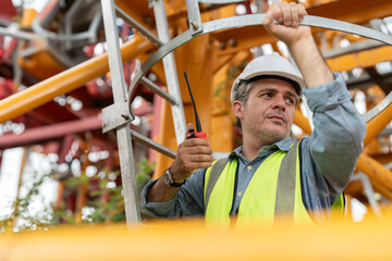 Asian male engineer wearing safety vests and helmet climbing metal ladder inspection and maintenance tower crane at construction site.