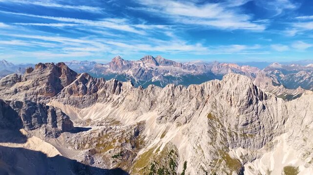 rone footage of the Dolomites panoramic  mountain range under a clear blue sky. Punta Sorapiss peak above glacial lake Lago di Sorapiss.  Ideal for travel, nature, and adventure projects.