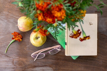 Books, eyeglasses and apples on wooden table on veranda with fall bouquet. Top view. Autumn still life. Nostalgia for the past. time of old age.