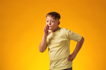 Child boy shouting and holding palm near opened mouth.