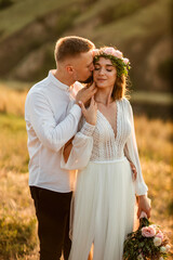 Fototapeta premium Beautiful couple in love hugging at sunset with mountains in the background.