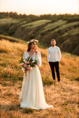 The evening summer sun creates a halo around a beautiful newlywed couple standing in the mountains