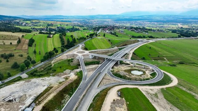 New fragment of highway under construction on Zakopianka road, Poland, over Klikuszowa village. Entrance and exit ramps, traffic circle. State in July 2024. Aerial view. Old road on the right
