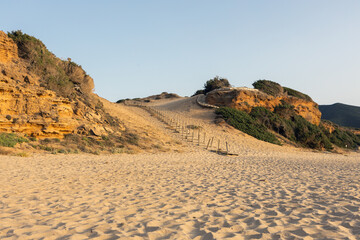 Sunlit Sandy Beach with Wooden Path. Di Scivu