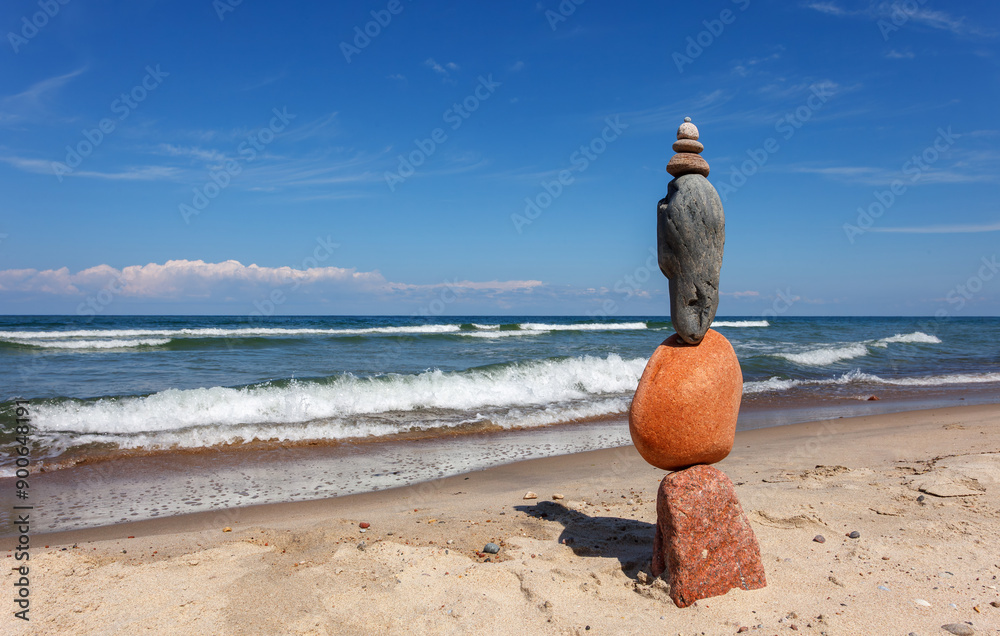 Wall mural Stone zen pyramid made of colorful pebbles on the beach against a stormy sea.