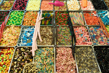 An assortment of colorful candies displayed in trays at a market.
