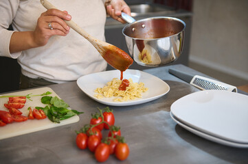Person preparing homemade pasta with fresh tomato sauce in a modern kitchen