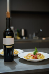 Elegant dinner setup with bottle of wine and pasta plates in a modern kitchen