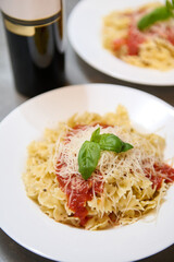 Delicious Italian pasta with tomato sauce, grated cheese, and basil in white plates
