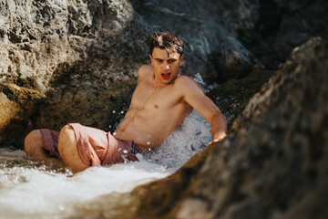 A young man cooling off in a mountain river, enjoying the refreshing water and natural surroundings while feeling re-energized.