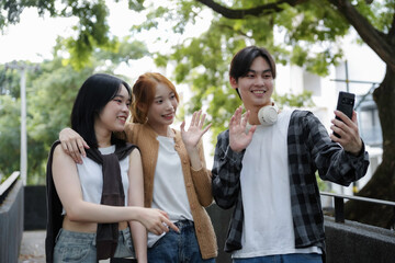 Three young asian friends are having a video call with a smartphone while walking in the city