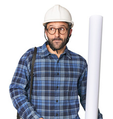 Hispanic male architect with plans confused, feels doubtful and unsure.