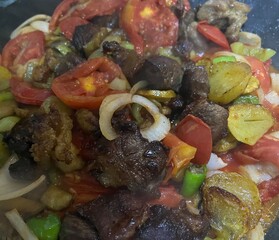 cooked in an oil pan a mixture of meat, tomatoes, onions, peppers, potatoes