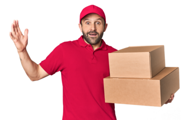 Hispanic male courier with boxes receiving a pleasant surprise, excited and raising hands.