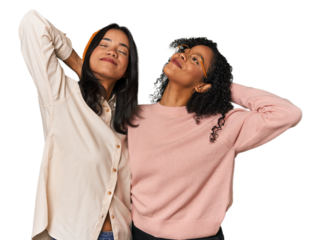 Young Latin friends together in studio feeling confident, with hands behind the head.