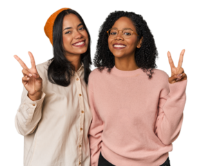 Young Latin friends together in studio joyful and carefree showing a peace symbol with fingers.
