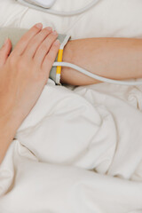 Person laying in bed with blood pressure cuff on arm, laptop on nightstand