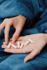 Woman holding pills wrapped in blanket with blue coverings over head and hands