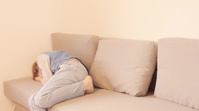 12-year-old boy in frustration, lying on sofa, punching pillows, experiencing teenage angst and tantrums, coping with emotions, angst and frustration, mental health