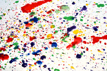 Background pattern created by splashes of acrylic paint, blue, green, red on a white sheet.