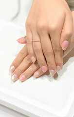 Hands with a glittery manicure resting on a UV lamp, showing off the finished nails with a touch of sparkle and elegance.