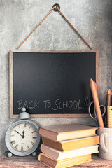 Time for school - blackboard, clock, books and school supplies on bricks background