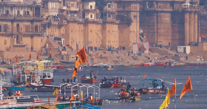 Varanasi, Uttar Pradesh, India. Many Boats are moored to the Ganga riverbank. Tourists boarding for an overnight boats ride on the Ganges River. Cityscape of Varanasi is visible - embankment in the
