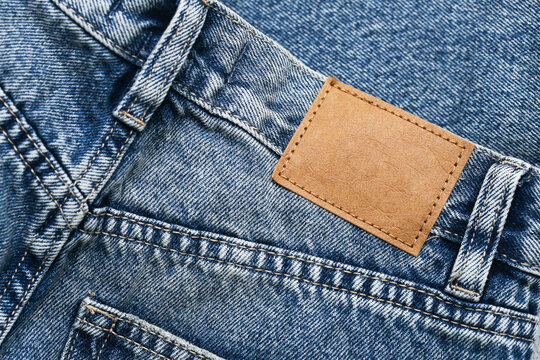 Empty copy space patch. Fashion detailed background. Brown leather label. Blank frame clothing tag. Blue jeans denim texture. Thread sew rectangle lines. Casual wear backdrop.