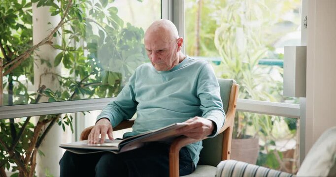 Home, relax and senior man with photo album, memory and retirement with nostalgia, grief and loss. Apartment, pensioner and mature guy with picture, gratitude and missing a loved one and photos