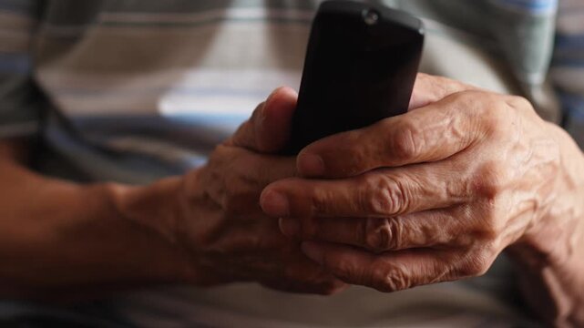 close-up of an elderly man's hand pressing buttons on a TV remote control, pensioner's leisure time watching TV scrolling through programs