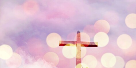 A wooden cross is shown against a backdrop of pink clouds. Concept of spirituality and reverence,...
