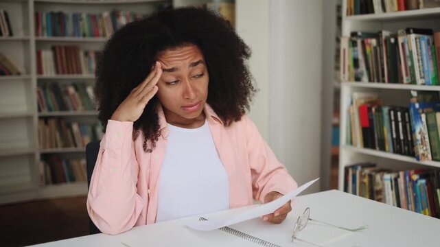 Upset young student got a bad grade on the exam feeling upset looking at test at classroom Stressed curly girl failed exam and feeling worried about having problems in university	
