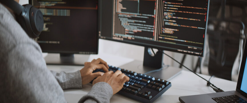 Young adult Asian male software developer coding program on desktop computer. Man work from home, remote working, freelance programmer job, smart digital nomad lifestyle concept. Close Up