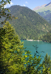 Obraz premium beautiful top view of turquoise lake ritsa in abkhazia among picturesque hills and green trees on a sunny summer day and copy space