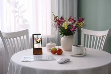 A Cozy and Inviting Workspace Featuring Beautiful Flowers and Modern Tech on a Table