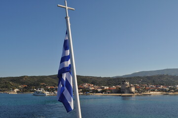 The Greece flag on the flagpole in the open blue sea