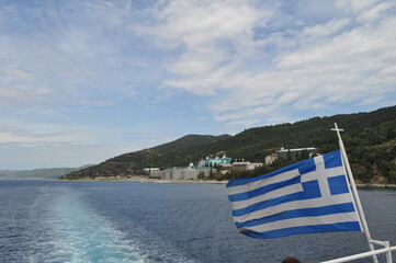 The Greece flag on the flagpole in the open blue sea