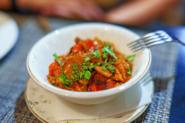 Georgian ajapsandali dish made of eggplant and vegetables is served in a plate on a table