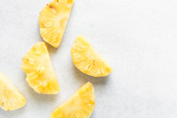 Top view of peeled chopped pineapples on a marble countertop, overhead view of chopped pineapples...