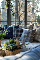 A close-up shot of the sofa in an English country house, with navy blue and grey checkered cushions arranged on it. The room is filled with large windows that flood it with natural light.