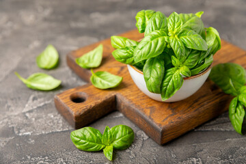 Green basil leaves on a textured wooden background. Kitchen herbs, spices. Fresh green organic basil. Vegan. Greens for salad. Place for text. Copy space.