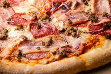 pizza close-up. Pizza with bacon, onion, salami, cheese. Lots of cheese. Thin crust. Garlic sauce