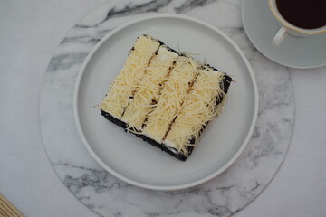 A piece of black cake topped with shredded cheese