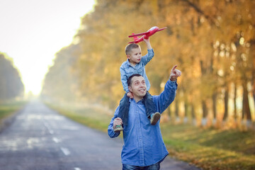 A Happy parent walks along the road with a child and an airplane in the park on nature travel