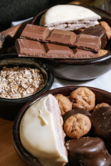 Chocolate chip cookies, dark and white chocolate bar, small bowl of oatmeal and nuts. International Chocolate Day.