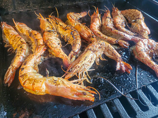 Langostinos a la parrilla cocin&aacute;ndose en una plancha con hierbas y especias arom&aacute;ticas.