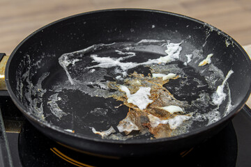 Dried, burnt leftovers in frying pan. The remains of burnt fried eggs 