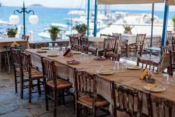Long table set for dinner at a greek restaurant with an ocean view