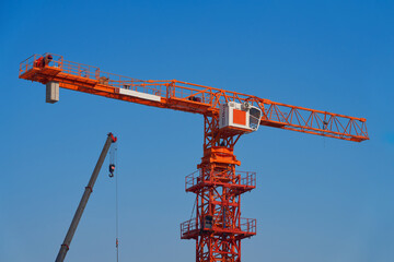 Multi-storey construction. The final stage of installation of a construction crane. A fragment of the crane against the blue sky.