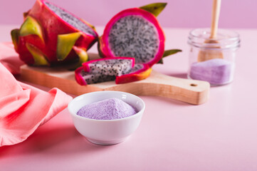 Pink matcha powder in a bowl and fresh dragon fruit on the table